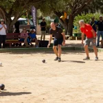 Pemandangan olahraga petanque di fopikotagorontal.org, pemain berkompetisi di lapangan berpasir yang cerah.